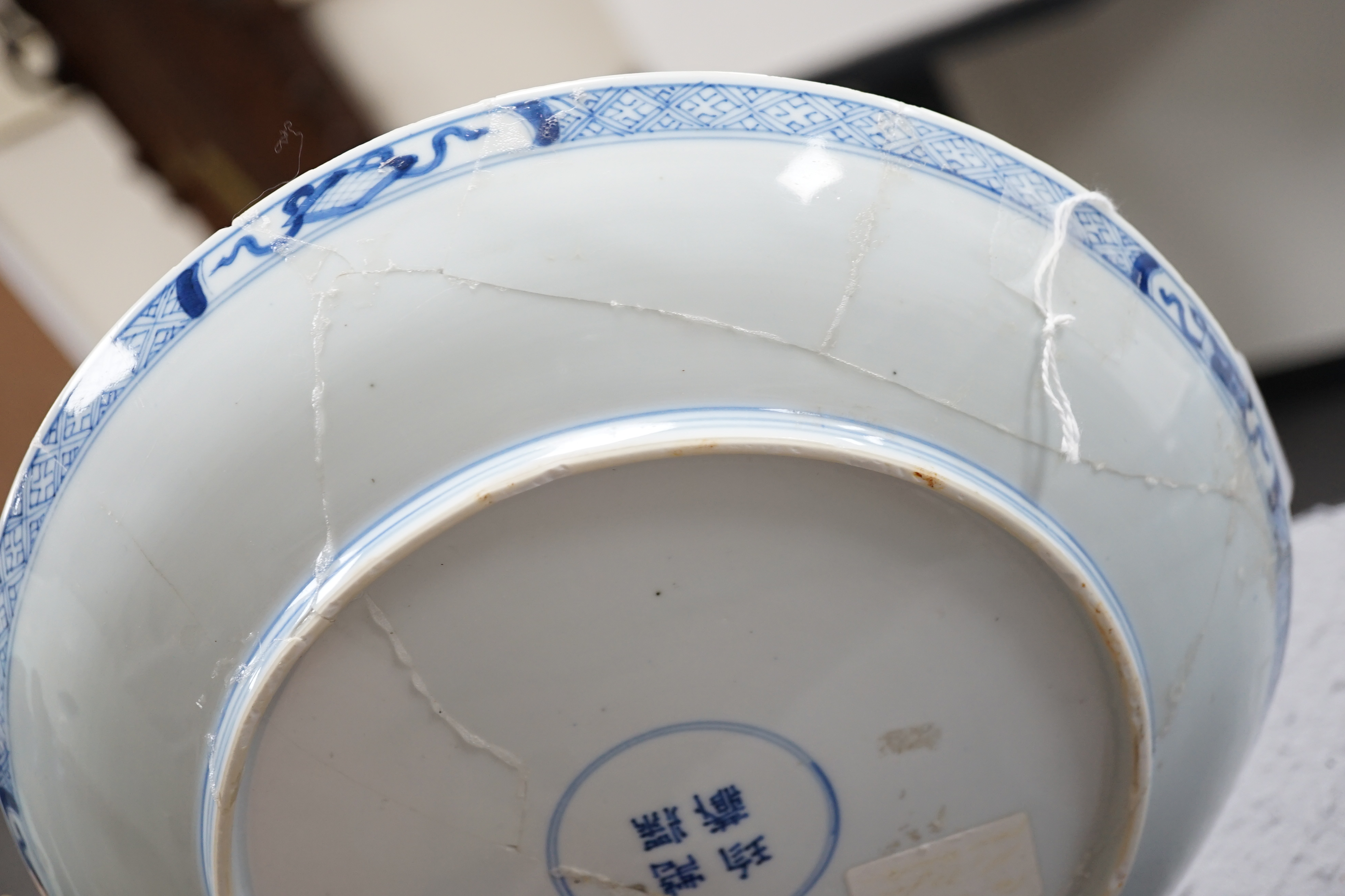 A Chinese blue and white dish, Kangxi period, broken and messily reglued